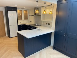 Navy blue & porcelain shaker style kitchen incorporating internal L.E.D glass cabinet lighting , Quartz work tops , Splashback & upstands , Belfast sink with bespoke recessed oak block cutting board , Range cooker & laminate oak effect herringbone flooring